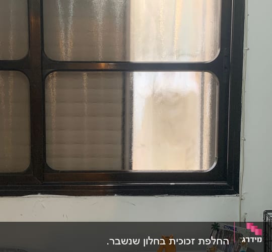 חלון זכוכית מטושטשת ומחוספסת במסגרת כהה בחדר מגורים